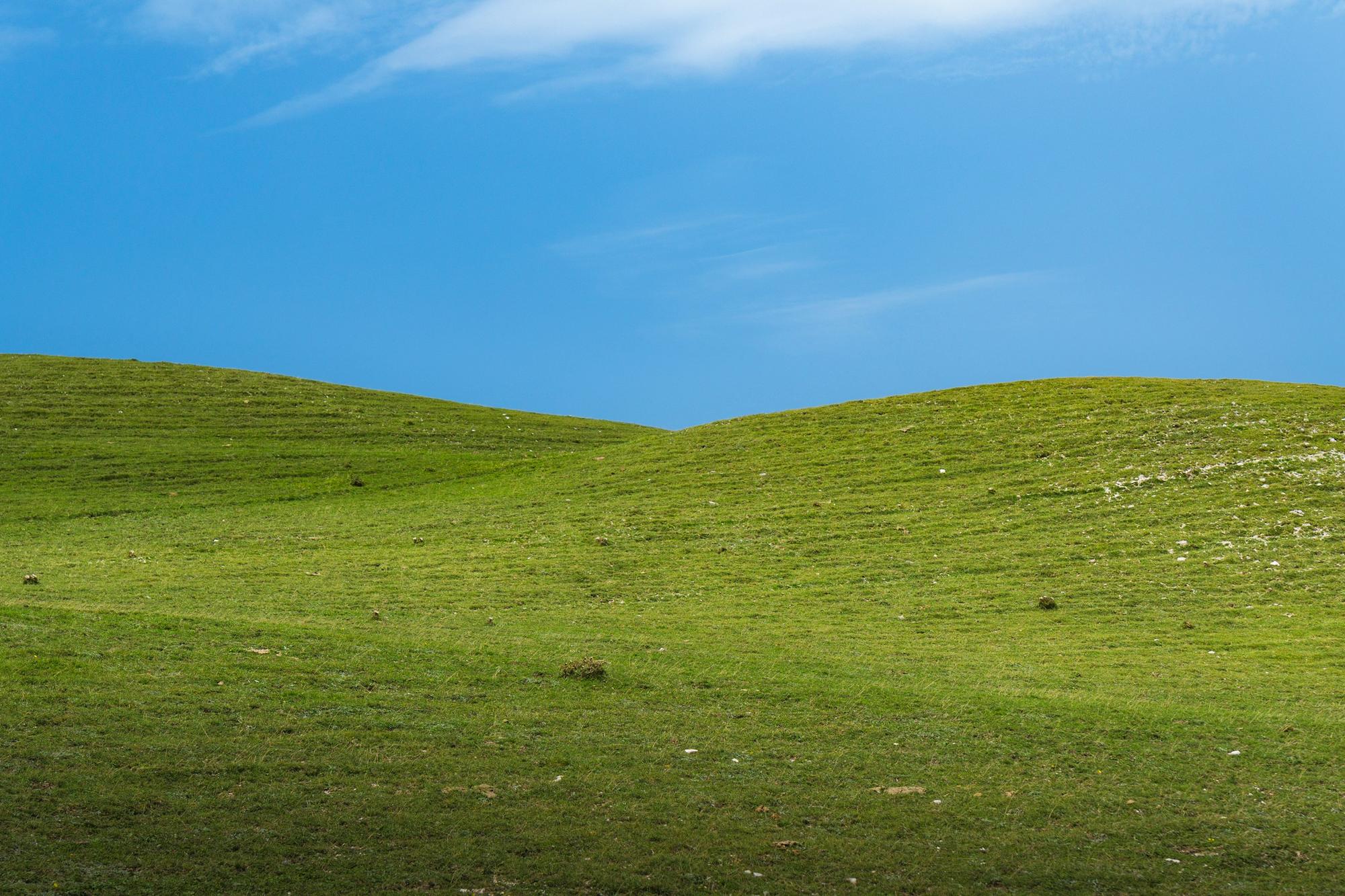 Valoviti zeleni griči pod modrim nebom